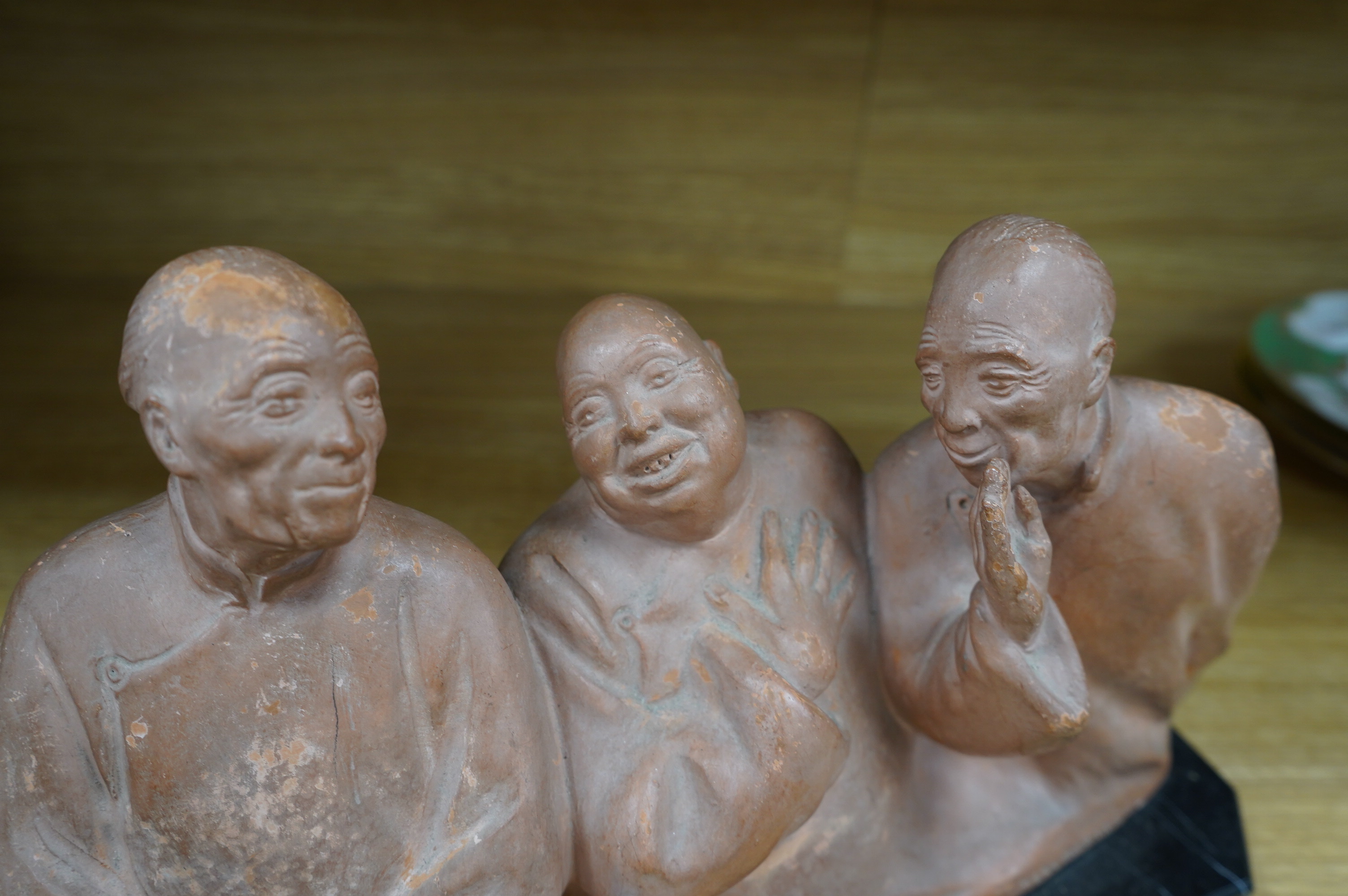 A French Art Deco terracotta sculpture of three seated Asian gentlemen, signature near base, 35cm high. Condition - fair